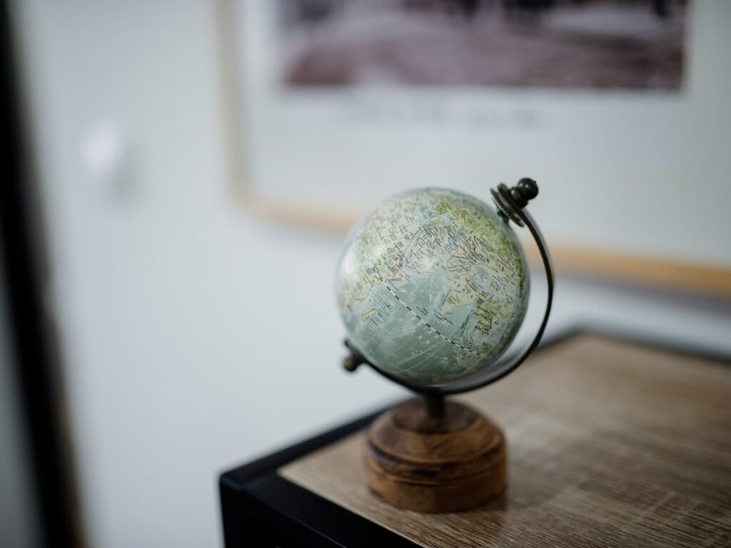 Decorative globe on a wooden stand placed on a desk in a modern room with artwork in the background