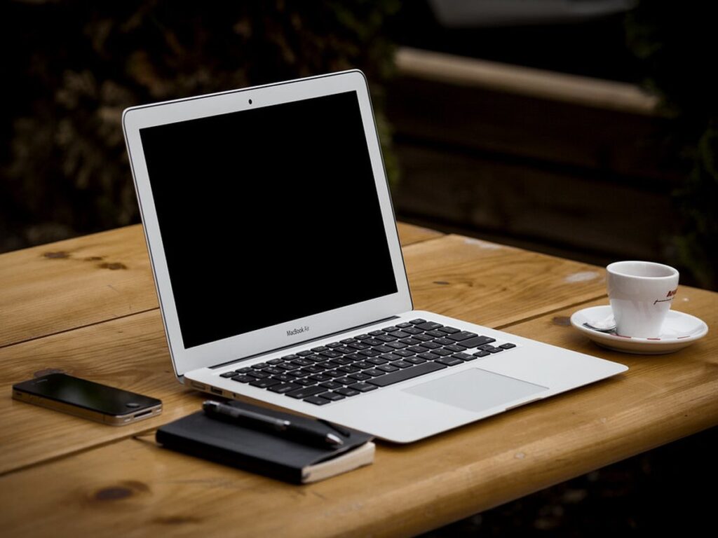 Apple Macbook Air on Wood Tabletop with Espresso Cup, Notepad, Pen, and iPhone